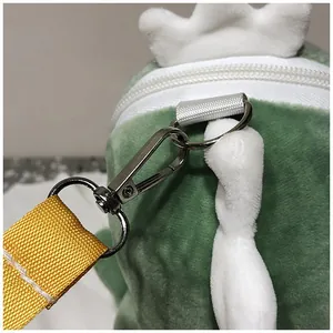 Detailed view of silver metal clasp and white zipper on cute green dinosaur plush bag.
