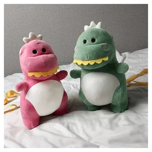 Pair of cute pink and green plush dinosaur crossbody bags resting on a soft white surface.
