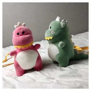 Detailed view of pink and green cartoon dinosaur plush crossbody bags on a bed.