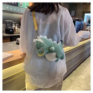 Cute green plush dinosaur crossbody bag worn by a model in a cozy cafe setting