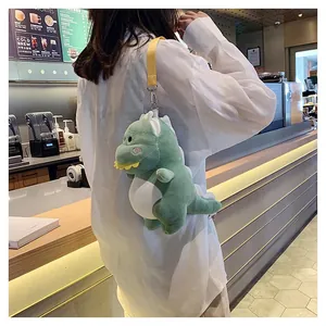 Detailed view of a cute green plush dinosaur crossbody bag worn over a white shirt in a cafe