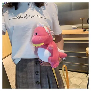 Close-up of a pink plush dinosaur crossbody bag worn by a model in a casual setting