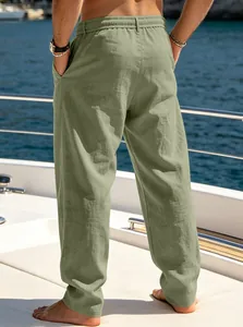 Back view of breathable men's loose sage green casual pants on a sunlit yacht deck