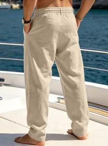 Detailed back view of men's loose beige linen-textured beach pants on a luxury yacht deck