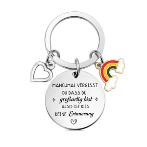 Primo piano di portachiavi in acciaio inox con ciondoli cuore, arcobaleno e disco inciso.
