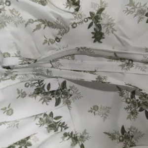 Detailed view of the green floral print and waist tie on a French style camisole dress.