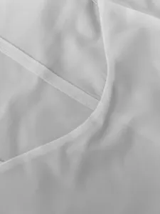 Close-up macro shot of premium white fabric and meticulous stitching on a summer dress