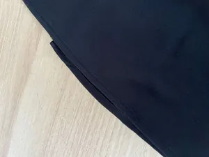 Macro detail of black dress fabric showing high-quality fine stitching and clean hemline