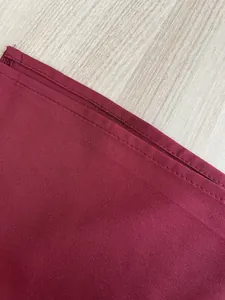 Close-up view of the neat stitching and hem on burgundy French style dress fabric