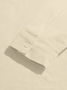 Close-up detail of cotton linen shirt cuff texture with a single button in beige color.
