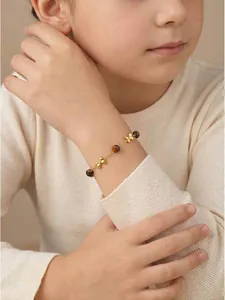 Detail view of a cute gold stainless steel butterfly bracelet for children with tiger eye beads