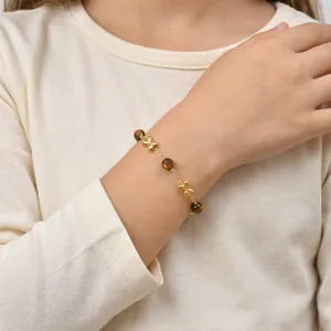 Golden children's bracelet with butterfly charms and tiger eye beads worn on a wrist