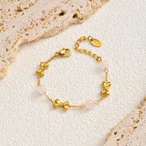 Detailed macro view of elegant gold bow bracelet featuring light pink beads on stone