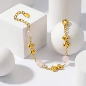 Macro detail of elegant gold bow bracelet featuring translucent pink beads and K18 tag