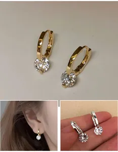 Close-up detail of sparkling round-cut zircon drop hoop earrings in gold and silver finish.