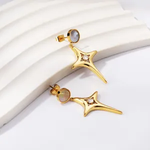 Gros plan de boucles d'oreilles en étoile dorée avec nacre et diamant central.