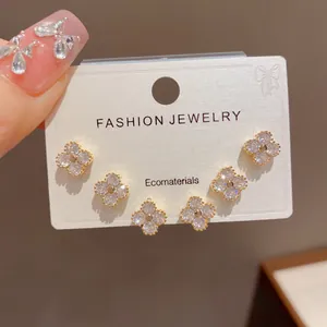 Detail of three pairs of dainty clover stud earrings with sparkling crystals on card