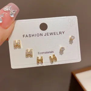 Elegant close-up of golden H-shaped and sparkling zircon stud earrings set on a display card