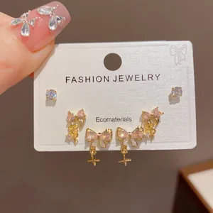 Close-up of elegant pink bowknot earrings set on white jewelry card, detail view.