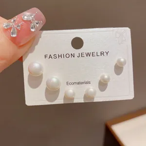 Detailed macro view of graduated white pearl stud earring set on display card