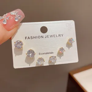 Close-up view of a minimalist zircon stud earring set on a white display card
