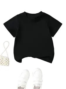 Minimalist kids solid black cotton T-shirt flat lay with white pearl bag and sneakers
