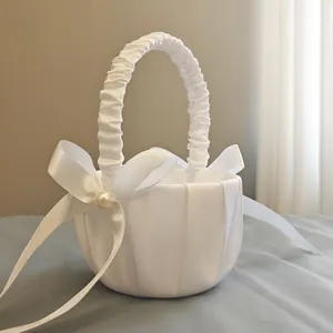 Close-up of white satin flower girl basket with elegant pearl and ribbon bow