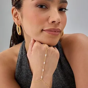 Close-up of minimalist 16k gold plated hand chain bracelet with pearl accents