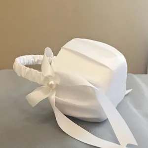 Detailed close-up of a white satin flower girl basket with an elegant pearl bow
