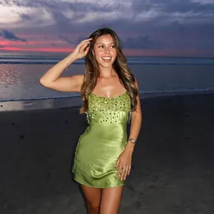 Robe bustier verte brodée de paillettes portée sur une plage au coucher du soleil