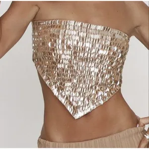 Détail macro d'une broderie de paillettes dorées sur un haut bustier sexy style bandana.