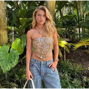 Vue détaillée d'un haut à paillettes dorées porté par un mannequin dans un jardin