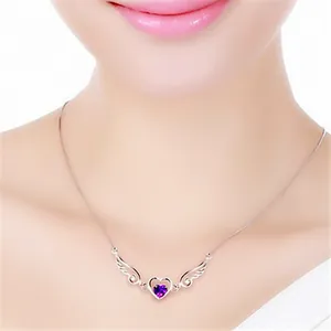 Close-up of angel wings heart necklace with purple stone on model neck