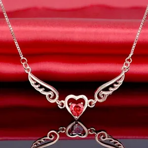 Close-up of angel wing heart necklace with a vibrant red heart-shaped gemstone