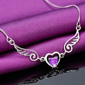 Macro detail of silver angel wing pendant necklace with purple heart-shaped stone