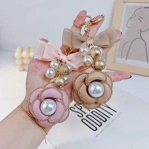 Fashionable camellia flower keychain featuring faux pearls and a double-layer bow pendant