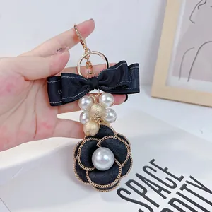 Detail of elegant black camellia flower keychain with pearls and ribbon bow
