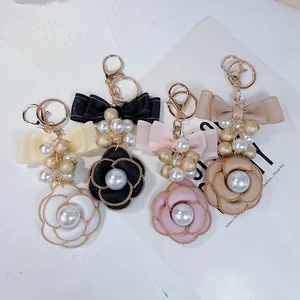 Detailed view of elegant camellia flower keychains with pearls and bows in four colors