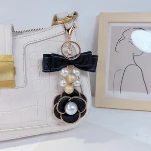 Detailed close-up of an elegant camellia bag charm with pearls and a double-layered black bow