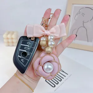 Detail of pink camellia keychain with pearl accents and a delicate mesh bow charm