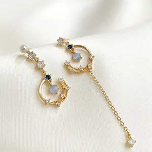 Detailed view of asymmetric star and moon earrings with gold finish and zircons