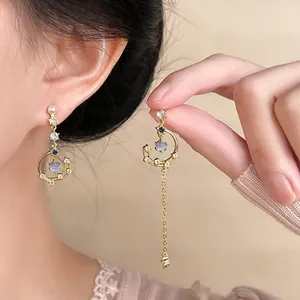 Detailed view of asymmetrical star and moon tassel earrings with blue zircon stones