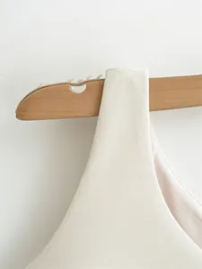 Detail view of white sleeveless dress showing textured fabric and shoulder strap detail.
