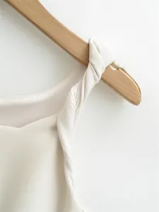 Close-up detail of cream sleeveless dress featuring a sophisticated twisted shoulder strap