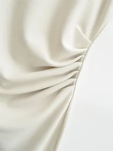 Detail view of elegant cream ruched dress showing fine fabric texture and pleats
