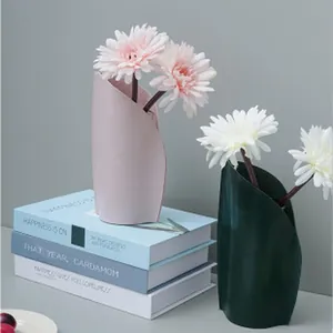 Close-up of minimalist pink and green leather cup sleeves used as decorative vases