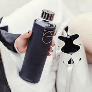 Hand holding a stylish black quilted leather water bottle sleeve with KD buckle