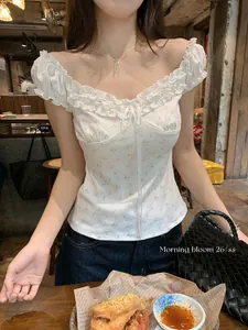 Detail view of a white floral off-shoulder top featuring ruffle trim and a slim fit