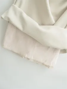 Close-up of high-quality lining and hem detail of an elegant beige midi dress for women.
