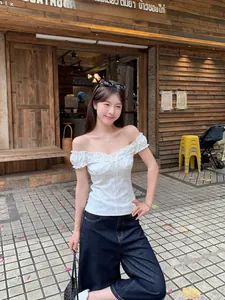 Detailed view of white floral off-the-shoulder top featuring ruffled wood ear edges